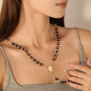 Macro shot of gold cross pendant and Madonna medal on a black beaded rosary necklace