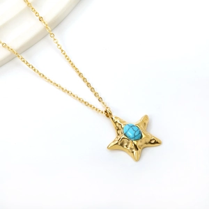 Macro view of golden starfish pendant with turquoise stone and fine chain link
