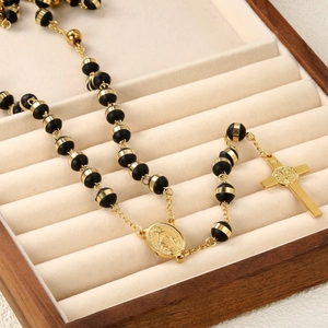 Macro detail of black rosary beads with gold cross and medallion in a wooden case