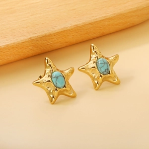 Detail of star-shaped gold earrings with turquoise stones and hammered metal texture
