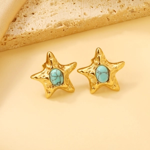 Close-up of golden starfish earrings with turquoise stones on a stone background