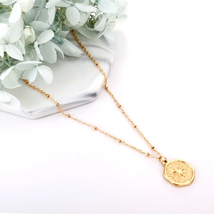 Vintage gold lucky star pendant necklace on a white marble stand with floral accents