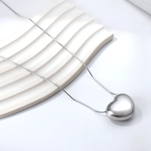 Polished heart pendant necklace with fine chain on minimalist wave display
