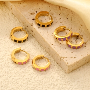 Minimalist wide gold hoop earrings with black, purple, and pink enamel inlay on stone surface