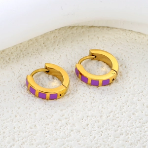 Detail view of gold-plated hoop earrings featuring purple enamel square accents