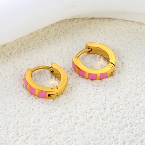 Macro shot of gold stainless steel hoop earrings with pink enamel square accents