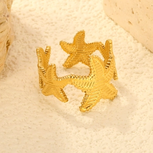 Bague ajustable étoile de mer dorée avec finition texturée sur fond de corail naturel