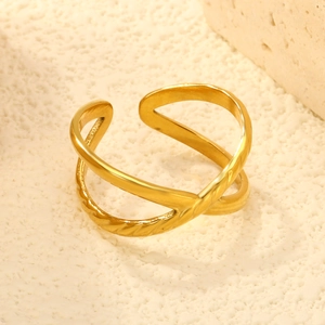 Détail macro d'une bague croisée dorée avec un anneau texturé sur fond de pierre