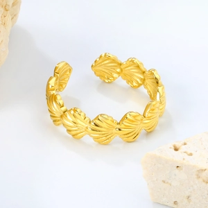 Goldener offener Muschelring mit nautischer Fächerstruktur auf weißem Stein