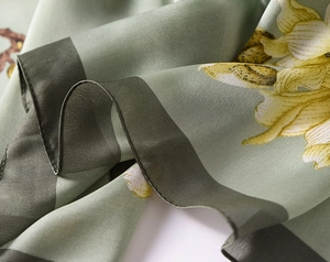Detailed macro view of magnolia floral print silk scarf with hand-rolled edges