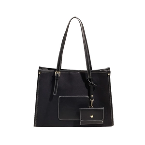 Minimalist black canvas tote bag with contrast stitching and small card holder charm