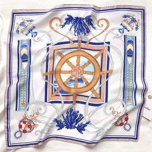 Detail of nautical silk scarf featuring navy anchor and ship wheel patterns on ivory fabric