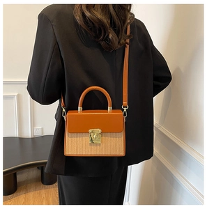 Detail view of contrast color box bag with golden lock and textured paneling