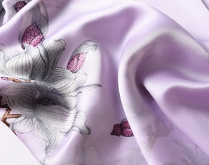 Detailed macro view of magnolia flower pattern on soft lavender silk satin fabric scarf