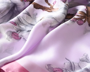 Detail of light purple silk scarf with magnolia print and pink hem texture