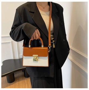 Detail of two-tone handbag with brown flap, white pleated texture and gold swivel lock