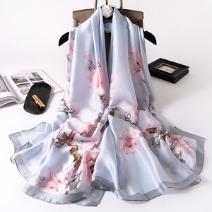Light blue silk scarf with pink magnolia floral print draped over a stylish handbag