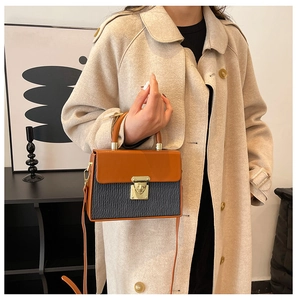 Detail view of contrast color box bag with brown flap and grey textured body on a model