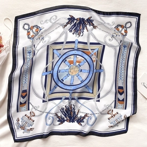 Macro view of nautical printed square silk scarf with anchor and steering wheel patterns