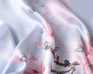 Detail of light blue silk scarf featuring pink magnolia print with elegant satin sheen