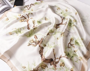 Detailed view of silk scarf with magnolia prints and soft texture on white background