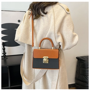 Detailed view of women's two-tone crossbody bag with black textured leather and orange flap