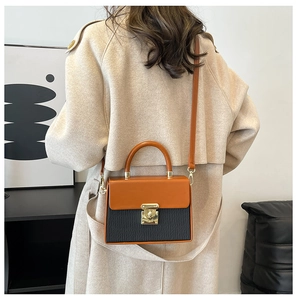 Detailed view of color-block crossbody box bag with gold buckle on a model in trench coat