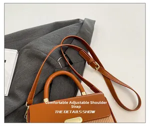 Detail of adjustable leather strap and metal buckle on contrast color box handbag