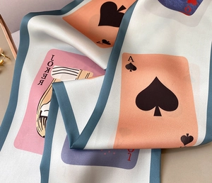 Detail eines Seidenschals mit Pokermotiven wie Joker und Pik-Ass in Pastellfarben