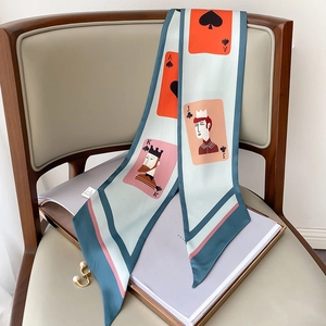 Detail eines Twilly-Schals mit Spielkartendruck in Petrol an einem Holzstuhl mit Perlen