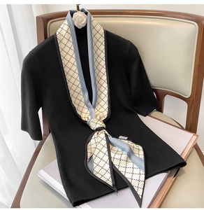 Détail d'un long foulard en soie à losanges associé à un pull en maille noir élégant