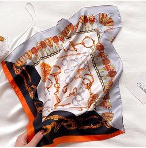 Détail d'un foulard en soie à imprimé chaîne avec motifs équestres en orange et gris