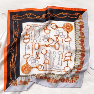Gros plan d'un foulard en soie carré avec des motifs de chaînes équestres et franges