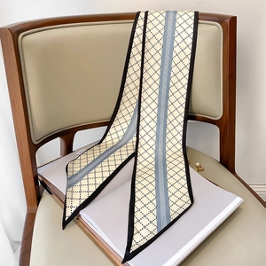 Détail d'un foulard étroit en soie beige à motifs losanges attaché sur une chaise en cuir