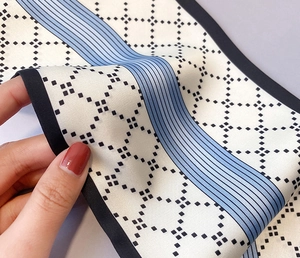 Gros plan montrant la texture soyeuse et les motifs géométriques du foulard étroit