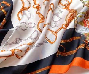 Détail d'un foulard en soie avec motifs de chaînes équestres et drapé souple