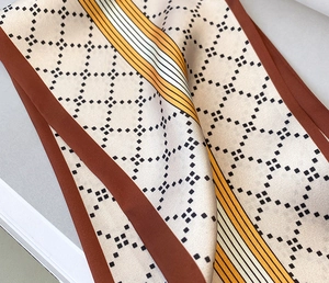Détail d'un foulard en soie à motif losanges avec finition satinée et rayures orange