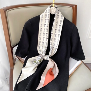 Detail of a beige narrow silk scarf with cartoon cat print tied on a black knit top