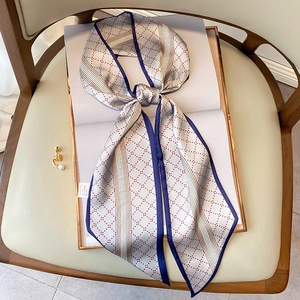 Petit foulard en soie à losanges avec bordure bleu marine sur un livre ouvert