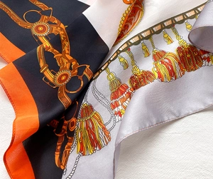 Détail d'un foulard en soie affichant des motifs équestres et des pompons colorés élégants