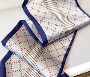 Détail d'un foulard soyeux avec bordure bleue, pois rouges et motifs à rayures