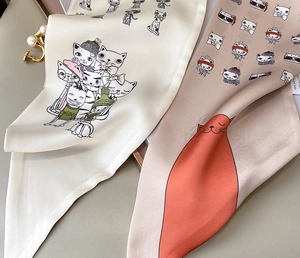 Macro shot of 100% silk skinny scarves with hand-drawn cat patterns and woven care label