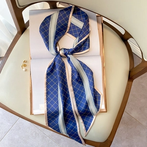 Foulard en soie bleu marine à losanges noué sur un magazine et une chaise