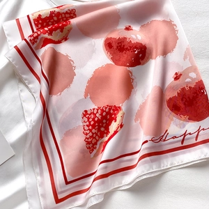Détail d'un foulard en soie rose avec motifs de grenades et texte Happy élégant