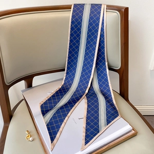 Détail d'un foulard en soie bleu marine à motifs dorés sur une chaise grise