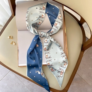 Elegant skinny silk scarf with rabbit floral print and polka dots tied on a white book