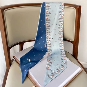 Detail of double-sided long silk scarf with blue origami rabbit print on a chair