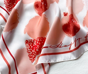 Détail d'un foulard en soie montrant des motifs de fraises et une texture satinée