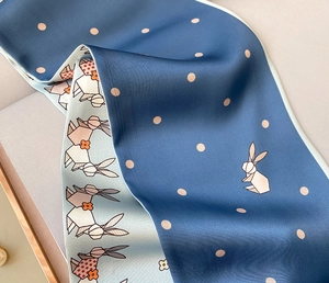 Close-up of silk scarf with rabbit pattern and polka dots showing fabric texture