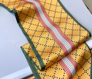 Détail d'un foulard en soie jaune gingembre avec motif en losange et bords rayés